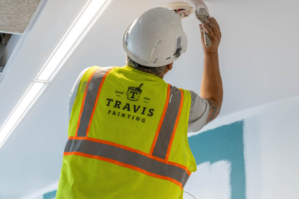 Bilt Marketing Photo of a J. E. Travis Painting, Inc. Employee painting wearing a branded safety vest.